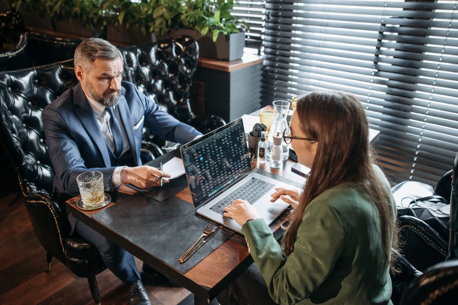 Two people discussing something beside a laptop