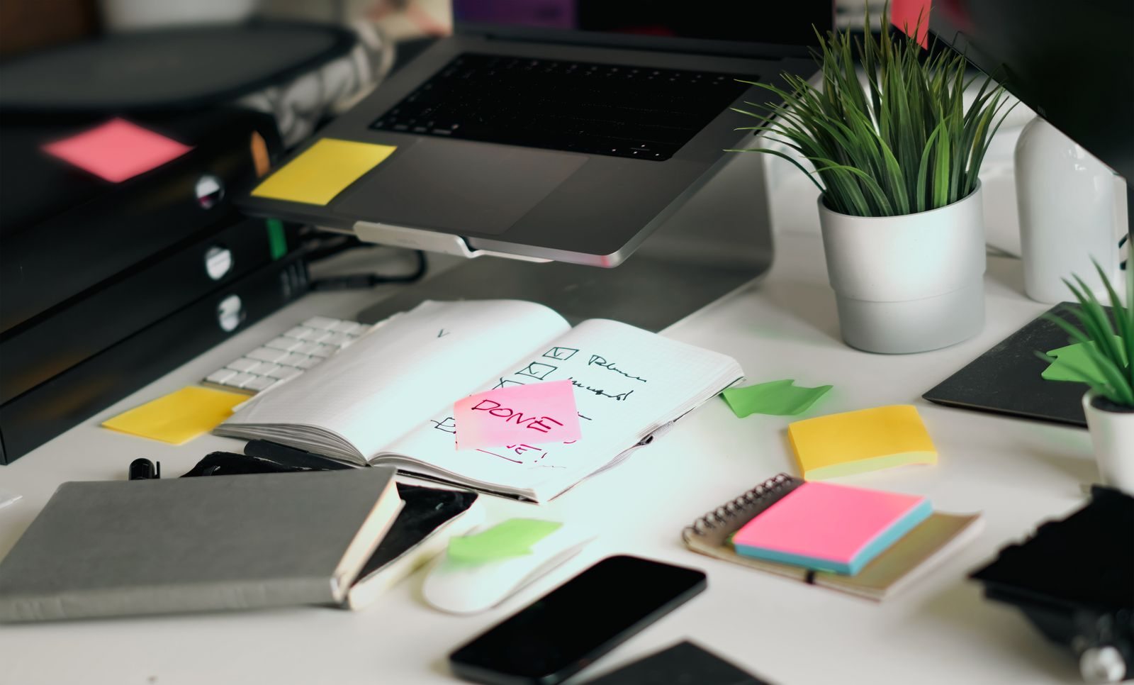 Notebook and task lists beside a laptop