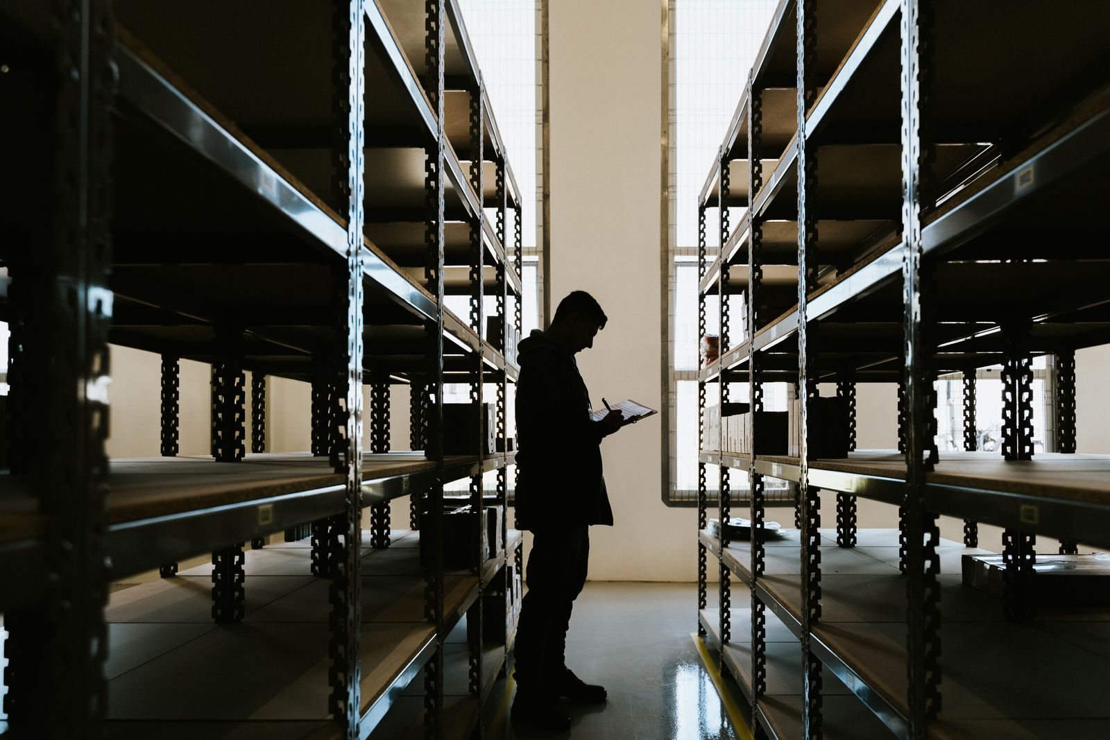 Person with a clipboard beside storage racks