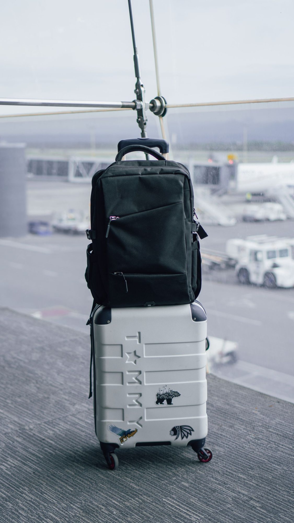 Backpack resting on a suitcase in an airport terminal