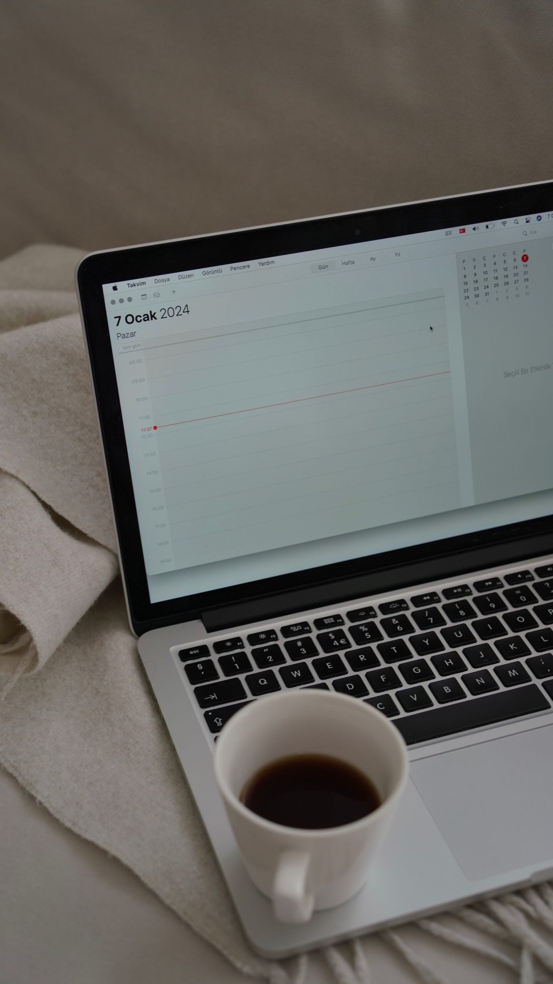 Digital calendar on a laptop beside a cup