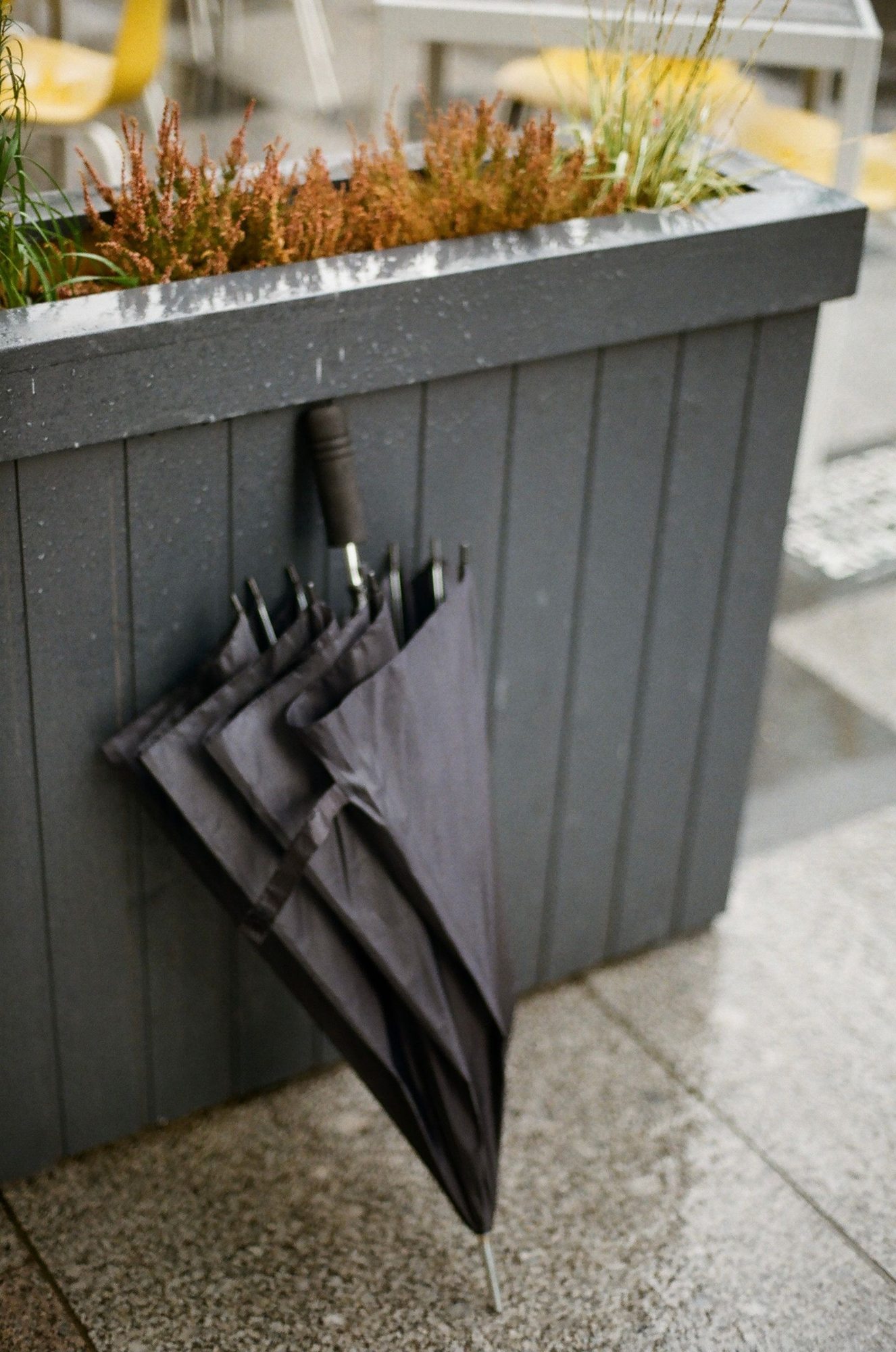 Closed black umbrella beside a planter