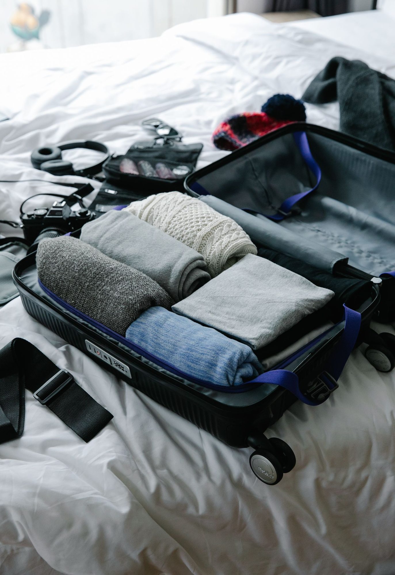 Open suitcase with clothes on a bed