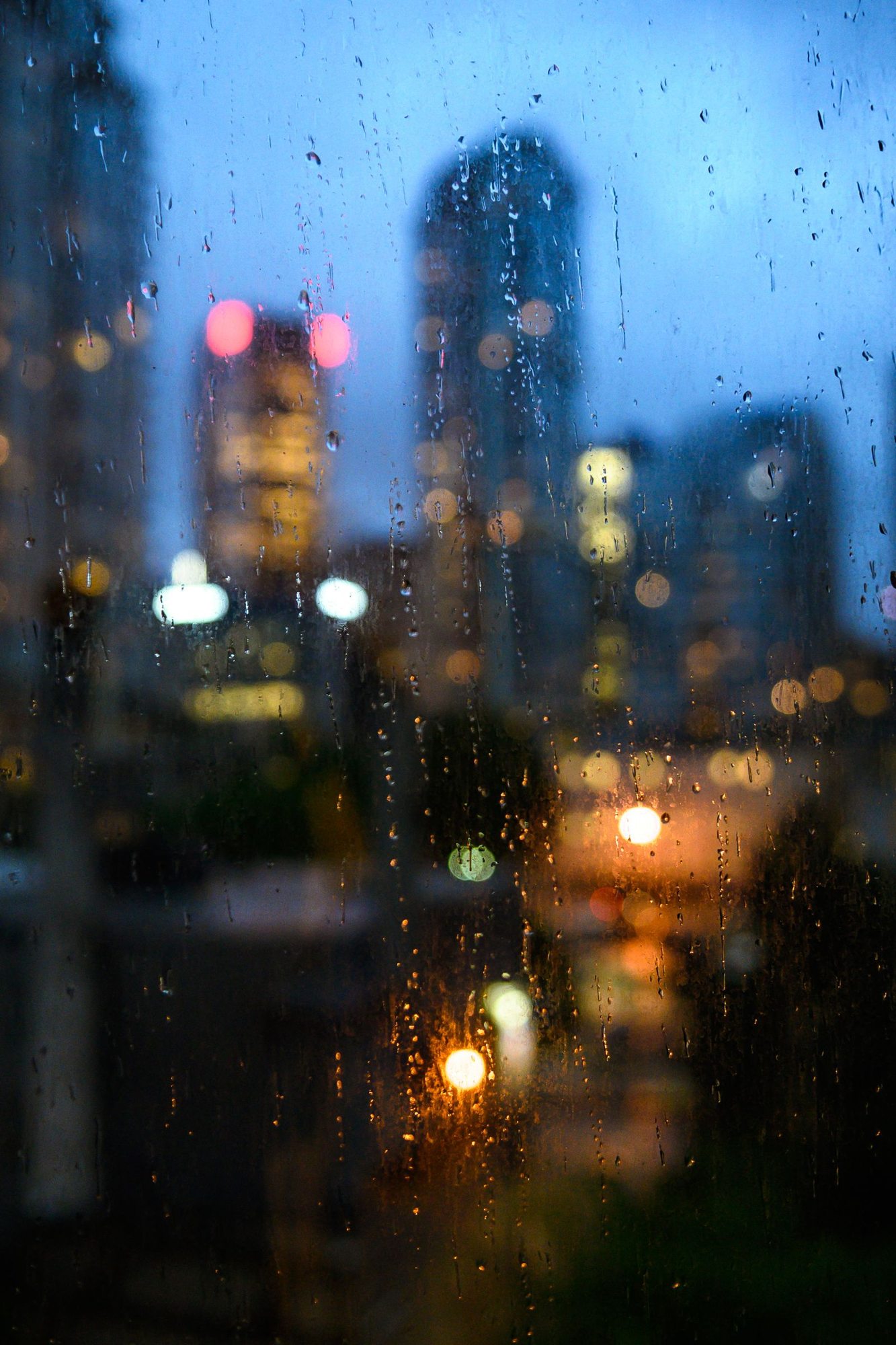 Raindrops on a window overlooking a city at dusk